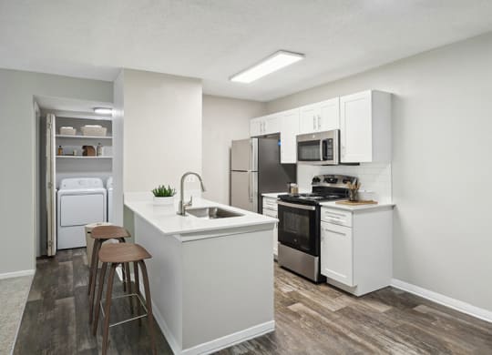 Model kitchen with White Cabinets and Wood-Style Flooring at Arbor Village Apartments located in Charlotte, NC.