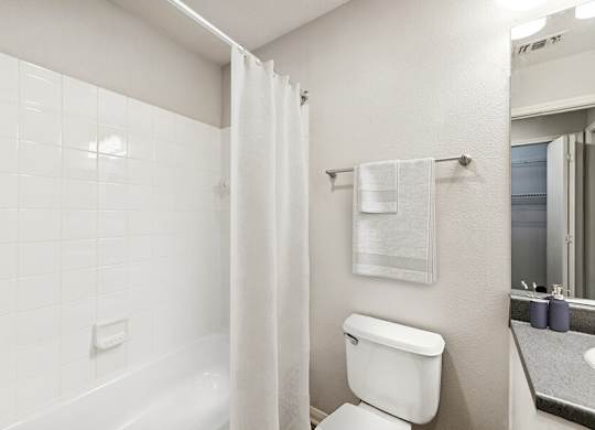 Model Bathroom with White Cabinets, Wood-Style Flooring & Shower/Tub at Lake Cameron Apartments located in Apex, NC.