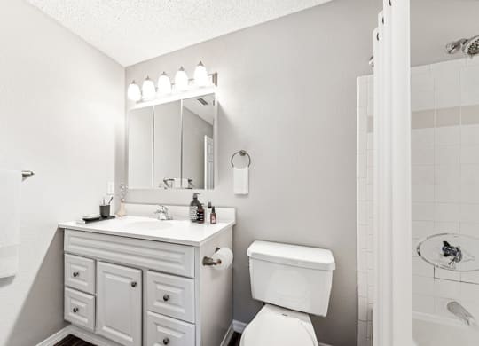 Model Bathroom with White Cabinets, Wood-Style Flooring and Shower/Tub at Commons at Haynes Farm Apartments in Shrewsbury, MA.