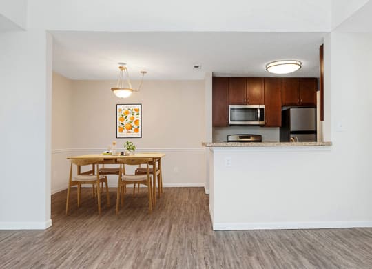 Model Dining Room and Kitchen Area with Wood-Style Flooring at The Commons at Haynes Farm Apartments in Boston, MA.