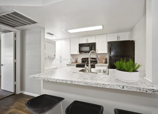 Model Kitchen with Wood-Style Flooring, White Cabinets and Washer/Dryer at Country Club Verandas Apartments located in Mesa, AZ.