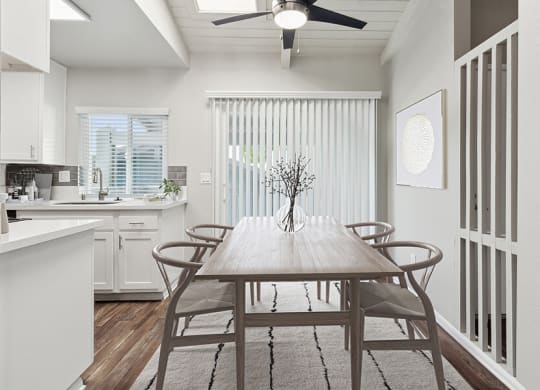 Model Dining Room and Kitchen Area with Wood-Style Flooring and Patio Accessibility at Colonnade at Fletcher Hills Apartments in El Cajon, CA.