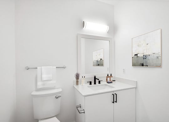 Model Bathroom with White Cabinets, Wood-Style Flooring and Shower/Tub at Stella Apartments located in New Carrollton, MD.