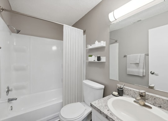 Model Bathroom with White Cabinets, Wood-Style Flooring and Shower/Tub at Spring Forest Apartments in Raleigh, NC.