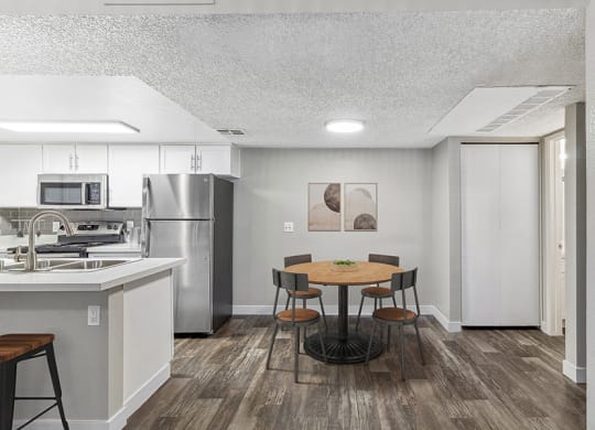 Model Dining Room and Kitchen Area with Wood-Style Flooring at Meadow Ridge Apartments in Las Vegas, NV.