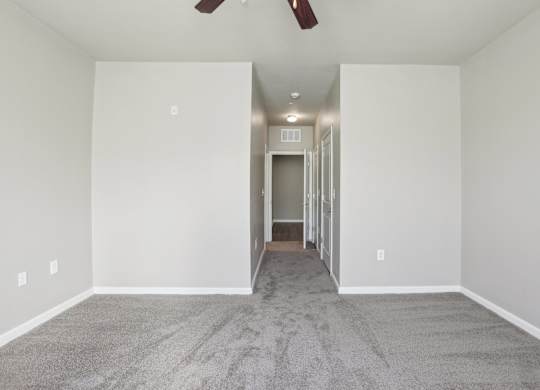 Model bedroom with a carpeted floor and a ceiling fan.
