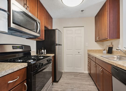 Model Kitchen with Brown Cabinets and Wood-Style Flooring at The Commons at Haynes Farm Apartments in Boston, MA.
