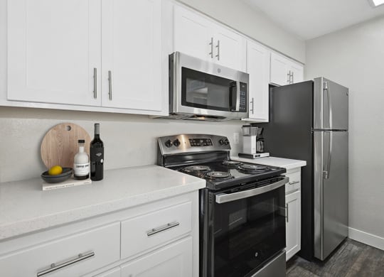 Model Kitchen with White Cabinets and Wood-Style Flooring at Crystal Creek Apartments in Phoenix, AZ.