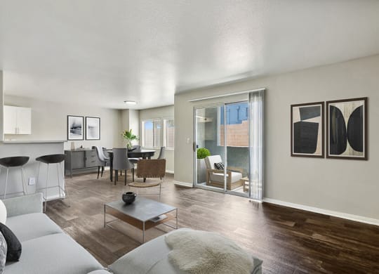 Model Living Room with Wood-Style Flooring, View of Dining Room & Patio Accessibility at Loma Vista Apartments in Las Vegas, NV.