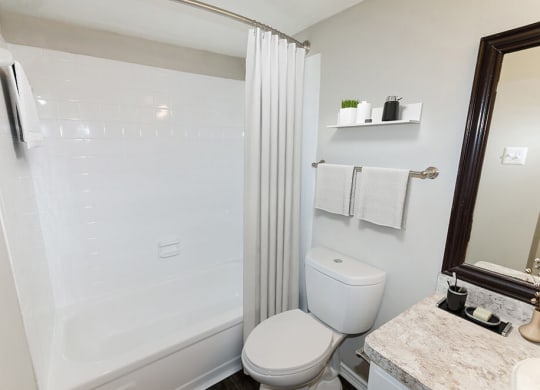 Model Bathroom with White Cabinets, Wood-Style Flooring and Shower/Tub at Cobblestone Apartments in Arlington, TX.