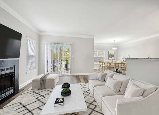 Model Living Room with Wood-Style Flooring, Fireplace and Patio Accessibility at Dulles Green Apartments located in Herndon, VA.