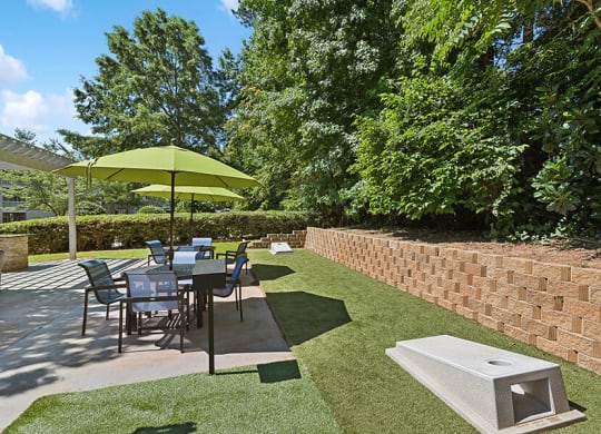 Outdoor Picnic Area with Lounge Furniture and Corn Hole Sets at Retreat at Stonecrest Apartments located in Lithonia, GA.