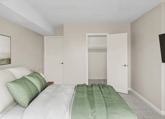 Model bedroom with a bed and a door to a closet  at Stone Ends apartments in Stoughton, MA