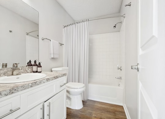 Model Bathroom with White Cabinets, Wood-Style Flooring and Shower/Tub at Westland Park Apartments in Jacksonville, FL.