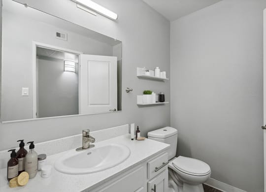 Model Bathroom with White Cabinets and Wood-Style Flooring at The Archer Apartments in Sacramento, CA.