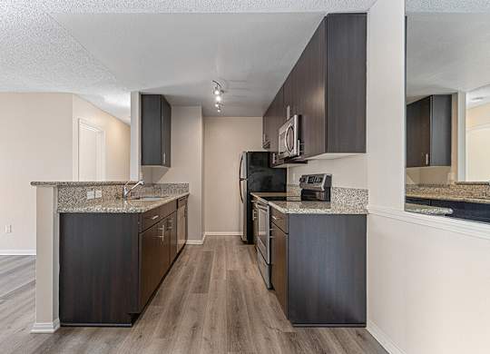 Model Kitchen with Dark Wood Cabinets and Wood-Style Flooring at Santa Fe Ranch Apartments located in Carlsbad, CA.