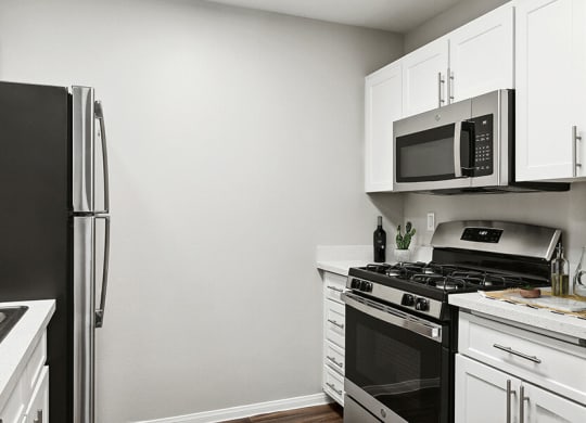 Model Kitchen with White Cabinets and Wood-Style Flooring at Loma Vista Apartments in Las Vegas, NV.