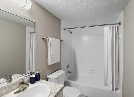 Model Bathroom with White Cabinets, Wood-Style Flooring and Shower/Tub at Abbington Heights Apartments in Antioch, TN.