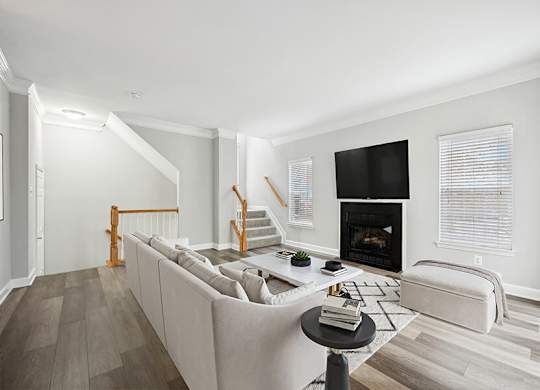 Model Living Room with Wood-Style Flooring, Fireplace and Patio Accessibility at Dulles Green Apartments located in Herndon, VA.
