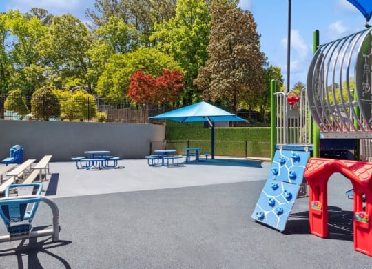 Community Playground and Outdoor Picnic Tables with Blue Canopy at Dunwoody Village Apartments in Atlanta, GA.