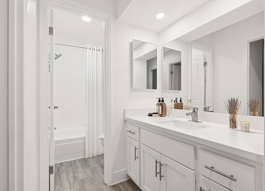 Model Bathroom with White Cabinets, Wood-Style Flooring & Shower/Tub at Horizon Apartments located in Santa Ana, CA.