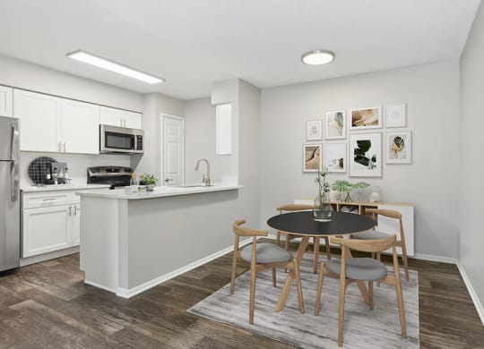Model Dining Room and Kitchen Area with Wood-Style Flooring at Grand Pavilion Apartments in Tampa, FL.