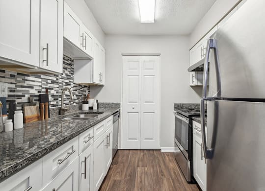 Model Kitchen with White Cabinets and Wood-Style Flooring at Lakeside Retreat Apartments located in Peachtree Corners, GA.