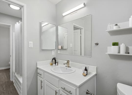 Model Bathroom with White Cabinets and Wood-Style Flooring at The Archer Apartments in Sacramento, CA.