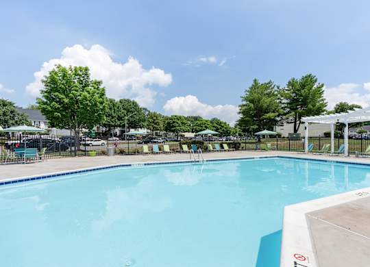 A large swimming pool with a blue tinted water and a white fence surrounding it.