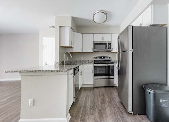 A kitchen with a refrigerator, oven, and microwave.