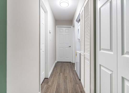 A long, narrow hallway with white doors and a white radiator on the wall.