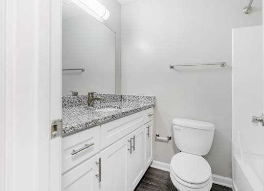 A white bathroom with a toilet, sink, and mirror.