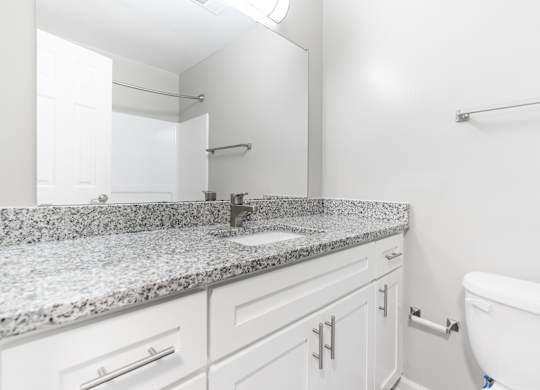 A white bathroom with granite countertops and a white tub.