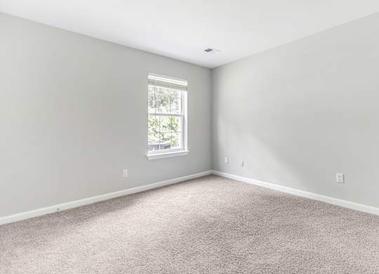 A room with a carpeted floor and a window.