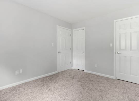 A room with two doors and carpeted floor.