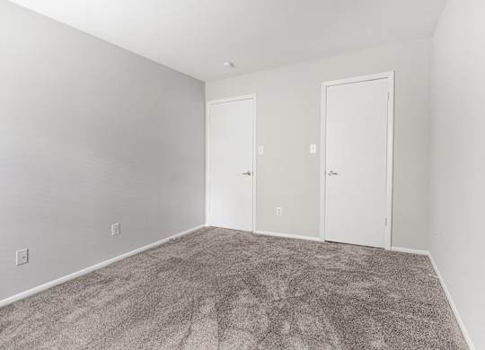 A room with two doors and carpeted floor.