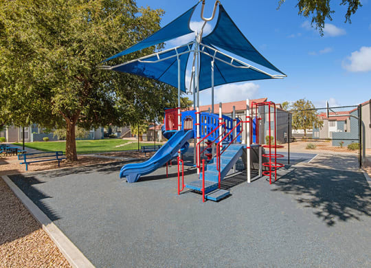Community Playground with a Slide and Blue Canopy at Peaks on 4th Apartments in Avondale, AZ.