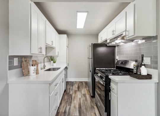 Model Kitchen with Wood-Style Flooring & White Cabinets at Forest Park Apartments in El Cajon, CA.