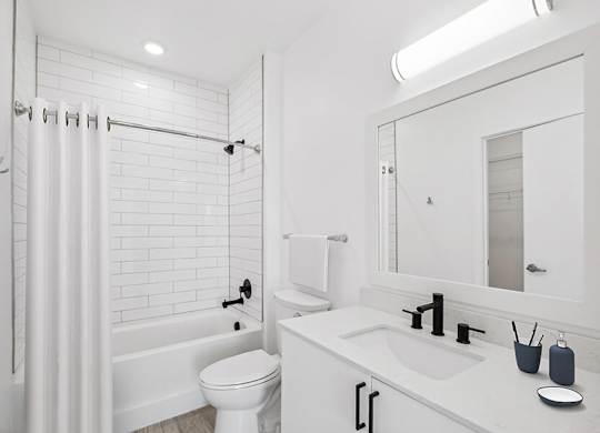Model Bathroom with White Cabinets, Wood-Style Flooring and Shower/Tub at Stella Apartments located in New Carrollton, MD.