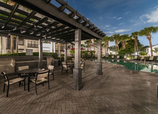 Outdoor BBQ Area with Canopy and View of Pool at Rosehill Preserve Apartments located in Orlando, FL.