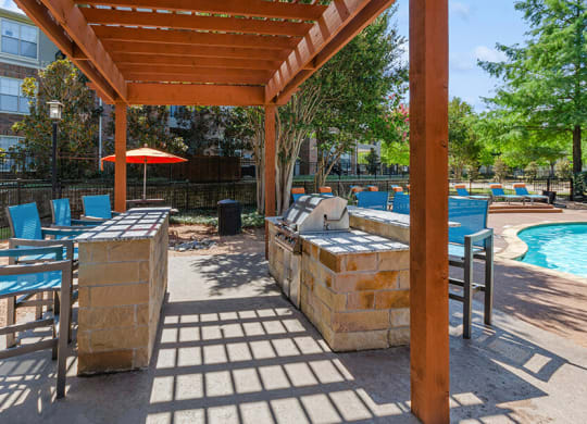 Outdoor BBQ Area with Furniture and Pool View at Belmont at Duck Creek Apartments in Garland, TX.