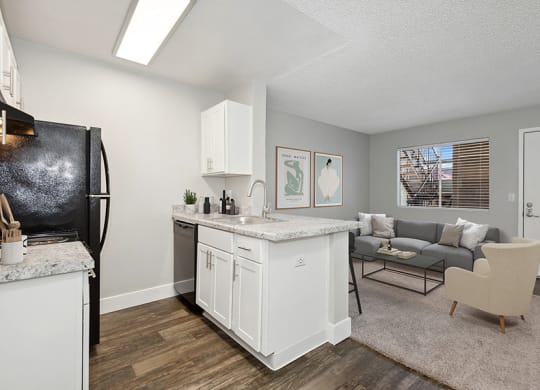 Model Kitchen with White Cabinets and Wood-Style Flooring with View of Dining Room at Stillwater Apartments in Glendale, AZ.