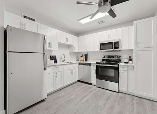 Model Kitchen with White Cabinets and Wood-Style Flooring at The Grove at Walnut Creek Apartments located in Walnut Creek, CA.