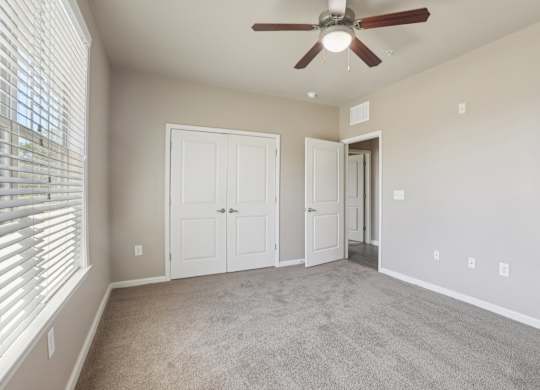 Model bedroom with a ceiling fan and two doors.