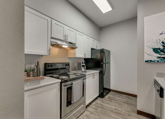 Model Kitchen with White Cabinets and Wood-Style Flooring at Landings at Morrison Apartments located in Gresham, OR.