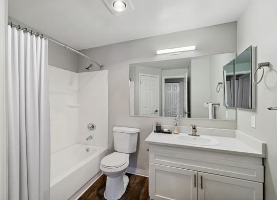 Model Bathroom with White Cabinets, Wood-Style Flooring and Shower/Tub at Central Flats Apartments in Kent, WA.