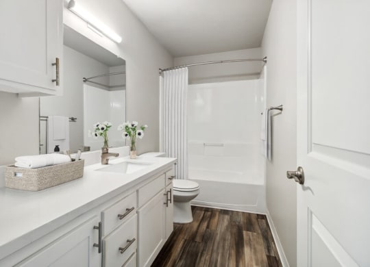 Model Bathroom with Bathtub/Shower, Wood-Style Flooring & White Cabinets at Forest Park Apartments in El Cajon, CA.