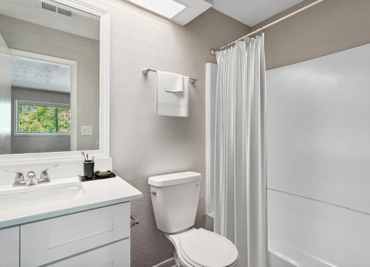 Model Bathroom with White Cabinets, Wood-Style Flooring & Shower/Tub at Lakeside Retreat Apartments located in Peachtree Corners, GA.