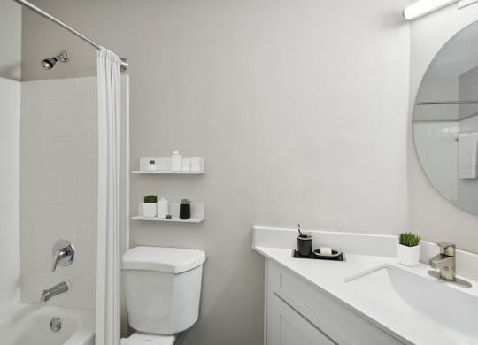 Model Bathroom with White Cabinets, Wood-Style Flooring & Shower/Tub at Arbor Village Apartments located in Charlotte, NC.