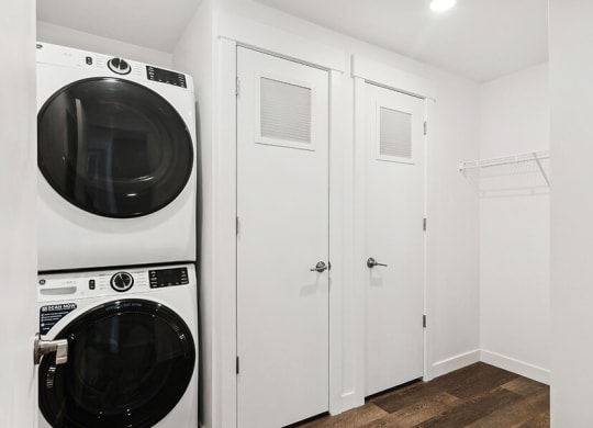 a washer and dryer in a white laundry room with white closets